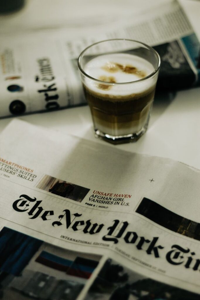 A glass of espresso with The New York Times newspaper on a table, creating a cozy morning vibe.
