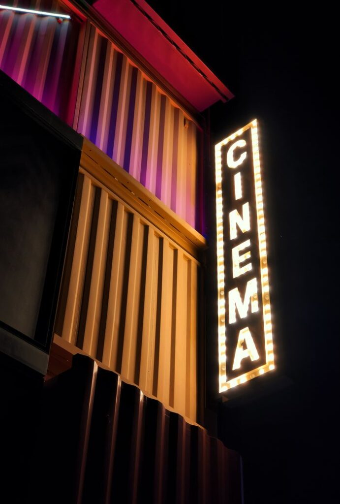 Brightly lit cinema sign against a modern architectural facade in Dubai at night.